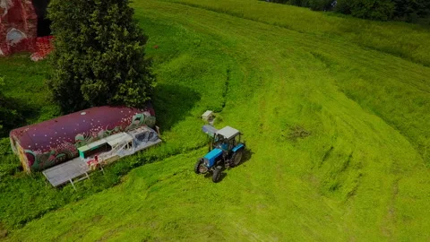 A blue tractor mows the grass at the destroyed church Stock Footage 169342812