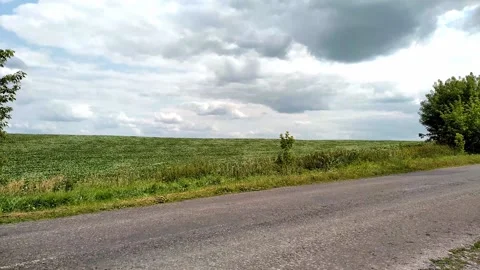 Blue tractor with an old trailer drives on the road along the fields. 스톡 동영상 157874878