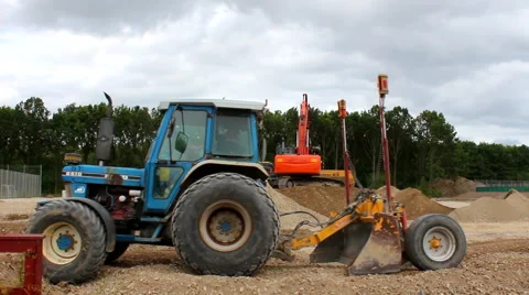 Blue tractor passing excavator doing construction work Stock Footage 52544187