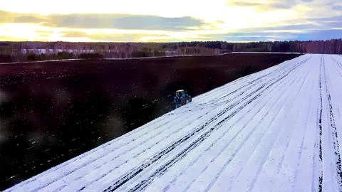 A blue tractor plows a field covered with snow. Watercolor illustration. Behi Stock Illustration