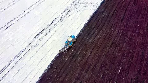 A blue tractor plows a field covered with snow. Watercolor illustration. Behi Stock Illustration