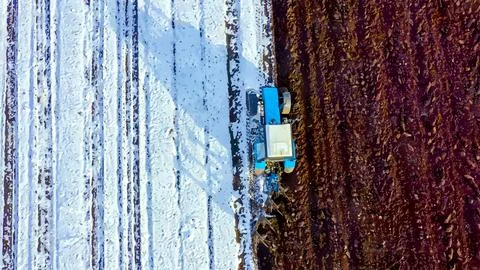A blue tractor plows a field covered with snow. Watercolor illustration. Behi Stock Illustration