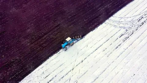 A blue tractor plows a field covered with snow. Watercolor illustration. Behi Stock Illustration