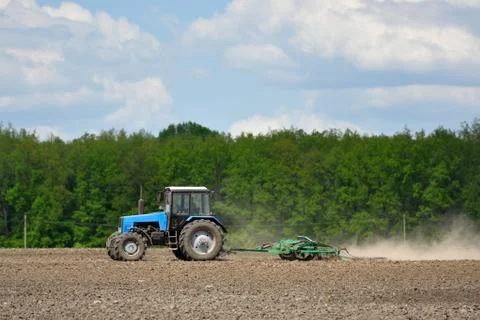 A blue tractor plows the field in the spring Stock Photos