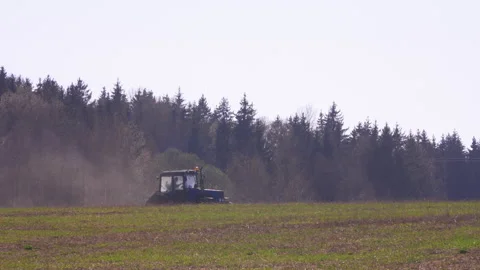 Blue tractor with a reverse plow plows a field against the background of a Stock Footage 147775626