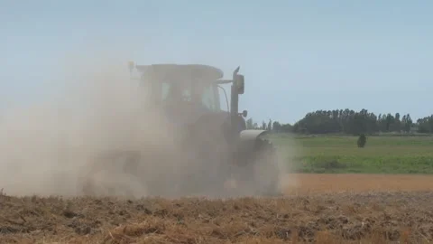Blue tractor working in agricultural field, plowing dry soil, kicking up a large Stock Footage 313878209