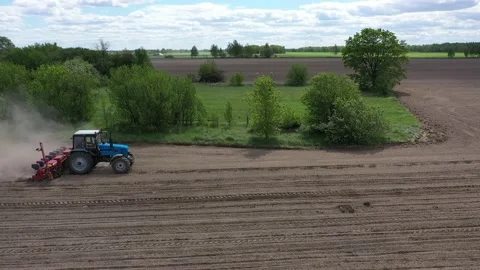 Blue tractor working on spring field, aerial view Stock-Footage 130616799