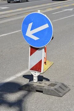 Blue traffic sign with arrow pointing left on street Stock Photos