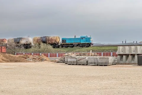 A blue train engine is moving freight cars along tracks, showcasing an indust 스톡 사진