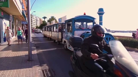Blue train on wheels drives on the promenade with tourists near by sea. Stock Footage 82908493