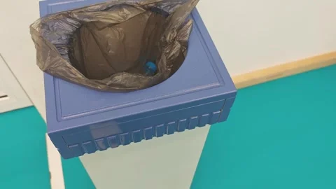 Blue trash bin with black plastic liner positioned on turquoise floor, showing Stock Footage 333263046