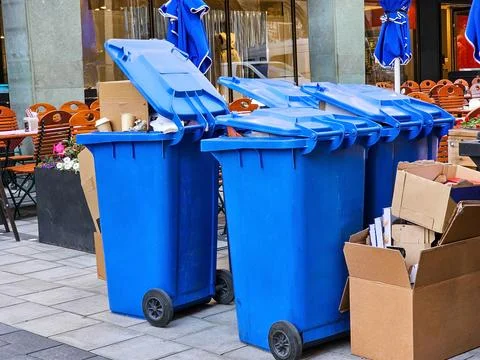 Blue trash can full of garbage Stock Photos