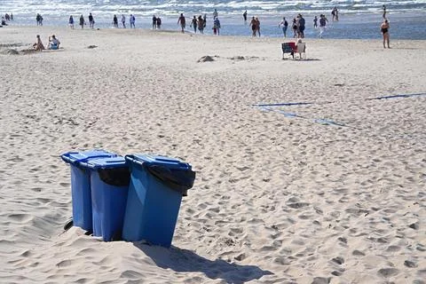 Blue trash containers installed directly on the sandy beach. Stock Photos