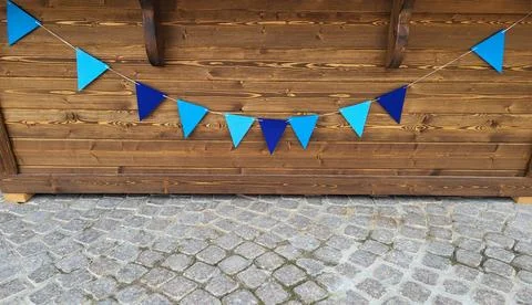 Blue triangular flags are hanging on the wooden background of the wall Stock Photos