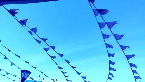 Blue triangular flags fluttering in the strong wind against the sky, tinted.. 库存照片