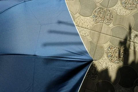 Blue umbrella canopy with hand shadow on patterned tile floor Stock Photos