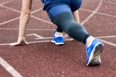 Blue-uniformed sprinter at a low start on the stadium's first treadmill Stock Photos