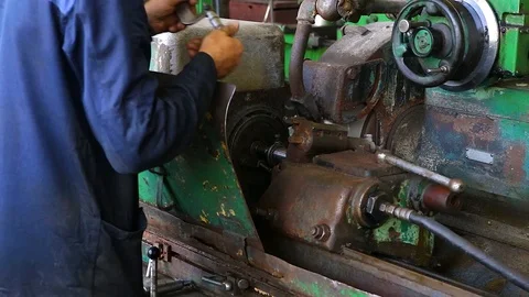 A blue uniformed worker measures a workpiece in a lathe Stock Footage 128603728