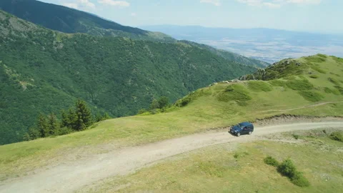 Blue vehicle on the edge of a cliff with mud offroad trail in the mountains Stock Footage 158151810