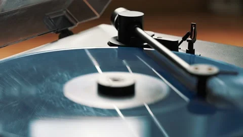 Blue vinyl record spinning and playing music on a black gramophone Stock Footage 220356807