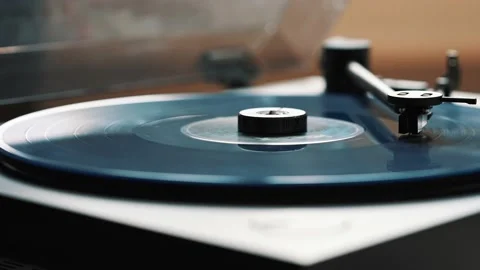 Blue vinyl record spinning and playing music on a black gramophone Stock Footage 220356809