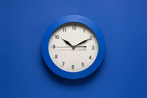 Blue wall clock with white face and black hands showing time management and p Stock Photos