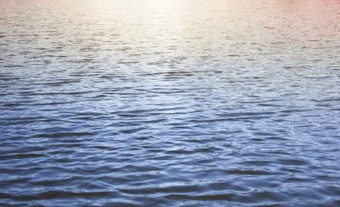 Blue water background. The sunset is reflected in the sea. Waves Stock Photos