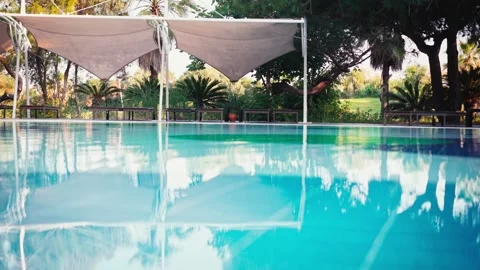 Blue water of the pool against the background of sunbeds and palm trees. Video stock 198486462