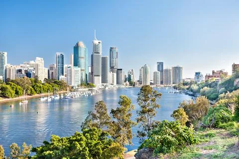 Blue water river surrounded by trees beside a modern city Stock Photos