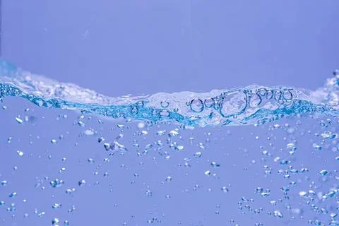 Blue water splash with bubbles and waves in clear liquid Stock Photos