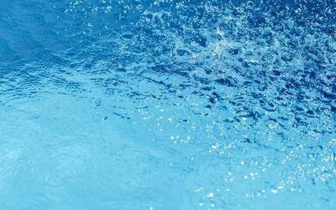 Blue water surface with bubbles and ripples. Sparkling reflections on water Stock Photos