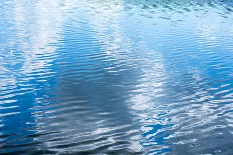 Blue water surface rippling with reflections of clouds, creating a calm Stockfoto's