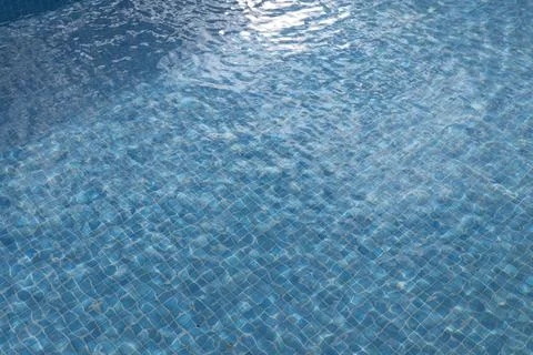 Blue water surface with sunlight reflections in a swimming pool Stock Photos