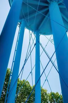 Blue water tower structure against sky and green trees Stock Photos