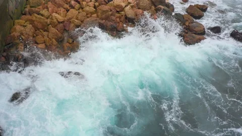 Blue waves black sea, beating brown rocks. Sea foam top view. Stones Stock Footage 143802828
