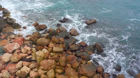 Blue waves black sea, beating brown rocks. Sea foam top view. Stones Stock Footage 143802834