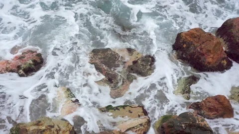 Blue waves of the black sea, beating brown rocks. Sea foam top view Video stock 143803144