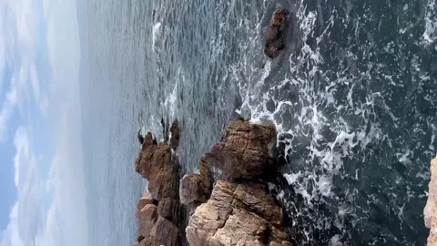 Blue waves crash on rocks cliffs - Vertical stock video Stock Footage 240326701