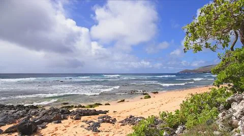 The blue waves of the Pacific Ocean roll over the rocky beach of the Hawaiian Stock Photos