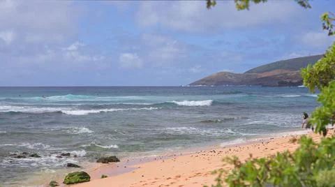 The blue waves of the Pacific Ocean roll over the rocky beach of the Hawaiian Stock Photos