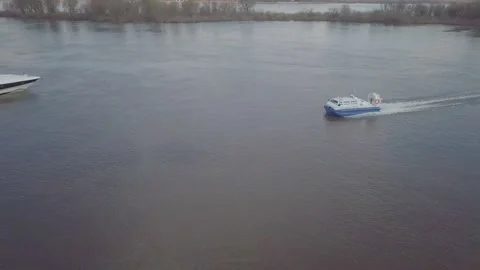 Blue white hovercraft sails along wide river past motorboat Video stock 155286778