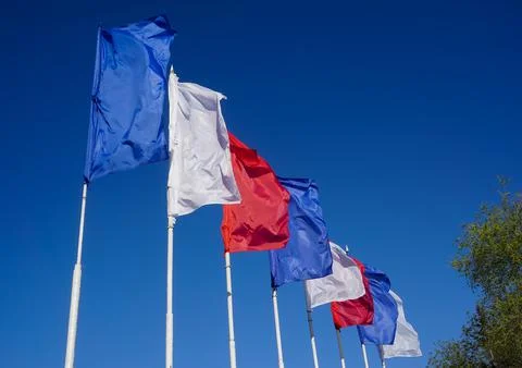 Blue-white-red flags on a blue sky background Stock Photos