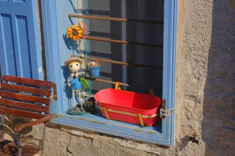 Blue window frame with red flower pot and small figurine Stock Photos