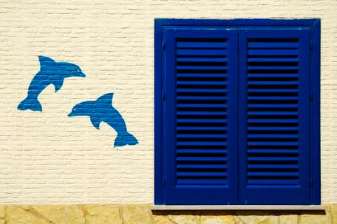 Blue window with painted two dolphins, Marettimo Island, Sicily Stock Photos