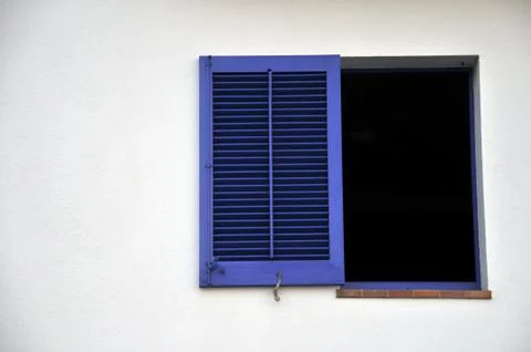A blue window shutter on a white wall.  Black window frame ideal to place your c Stock Photos