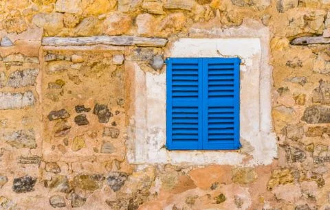 Blue window shutters and rustic stone wall of mediterranean house Stock Photos