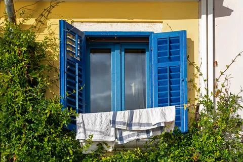 Blue window shutters with laundry drying outside. Bright blue shutters on a Foto stock