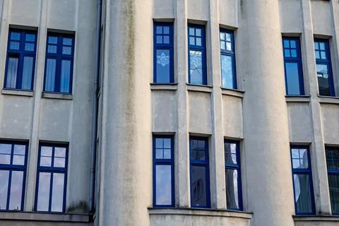 Blue windows on gray building facade Stock Photos