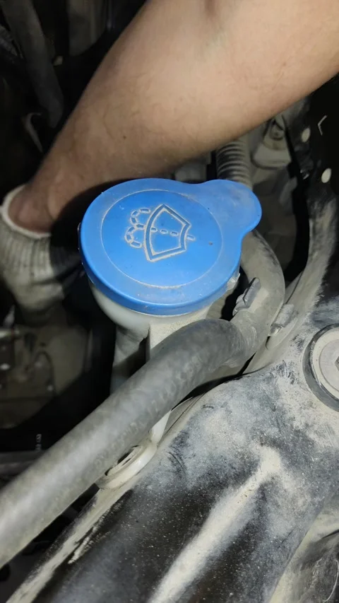 Blue windshield washer reservoir cap inside a dusty car engine Stock Footage 332240097