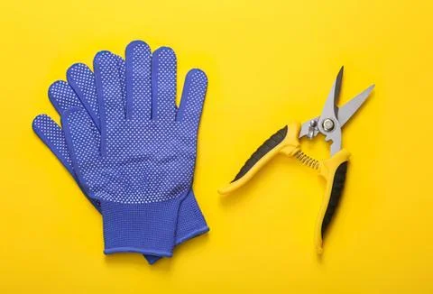 Blue work gloves and pruning shears on yellow background Stockfoto's